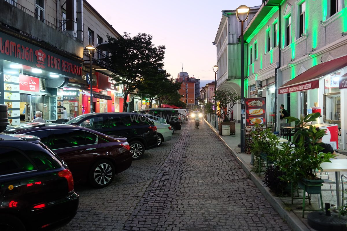 Evening street in Batumi Old Town with lit restaurant facades and cobblestones