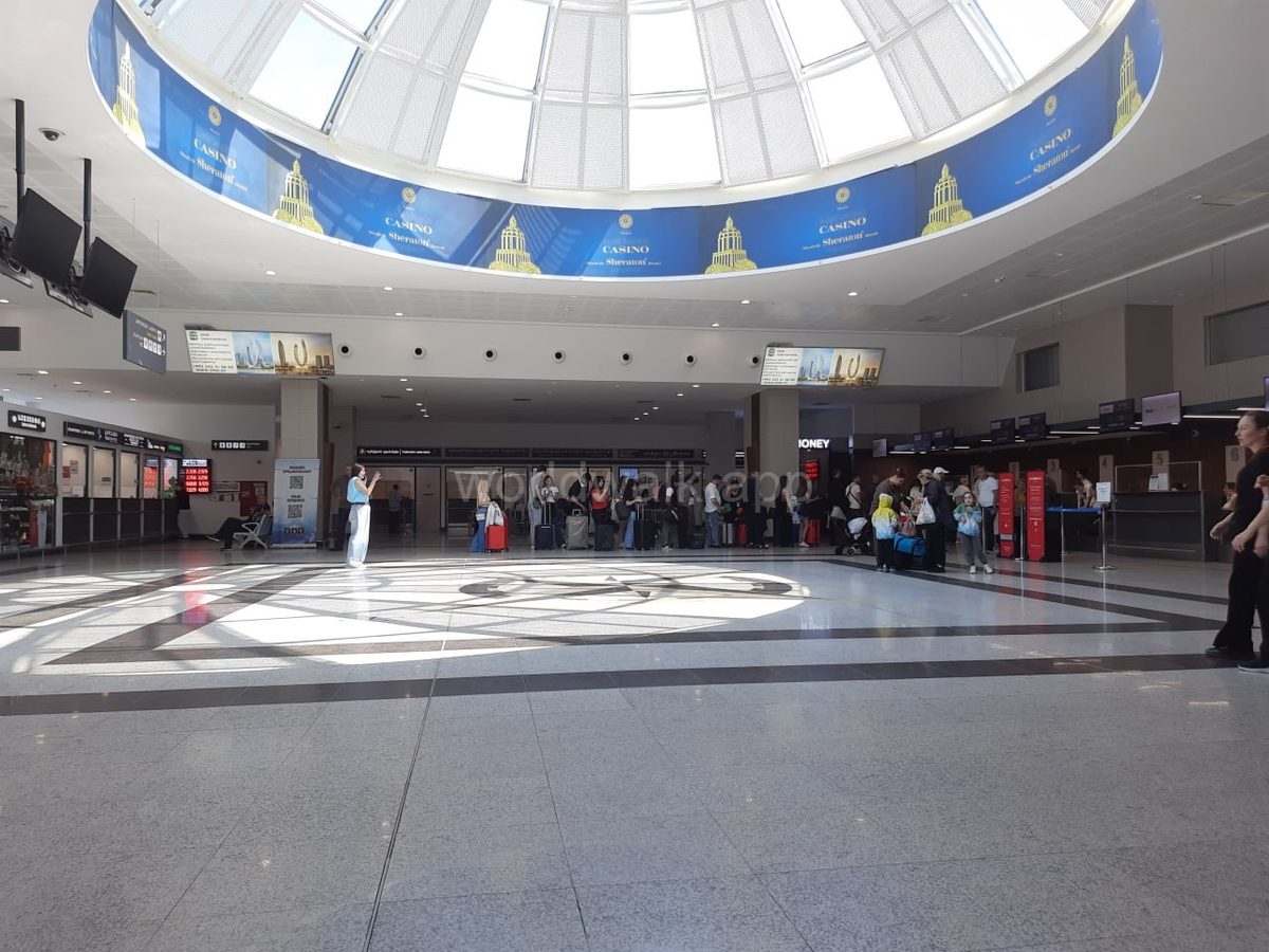 Arrivals hall inside Batumi Airport with dome ceiling and passengers with luggage